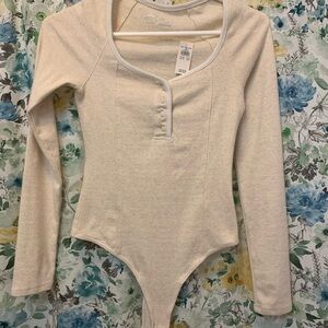 Snap bottom body suite in a beautiful cream color and button up top!